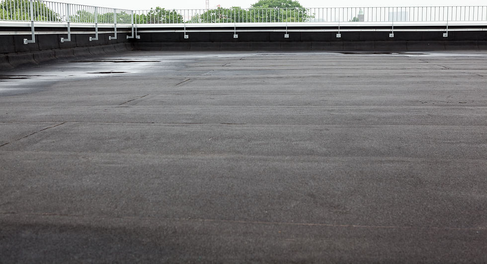 Flat, empty rooftop with black waterproof material, bordered by a white railing