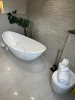A bathroom with a curved white bathtub and plush towels