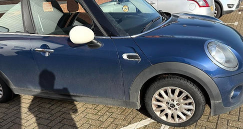 Side view of a blue hatchback car parked outdoors on a paved surface