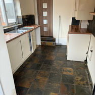 Modern kitchen with wooden countertops, slate floor tiles, and fitted cabinets