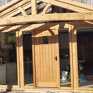 Wooden-framed doorway with a central door flanked by large glass panels
