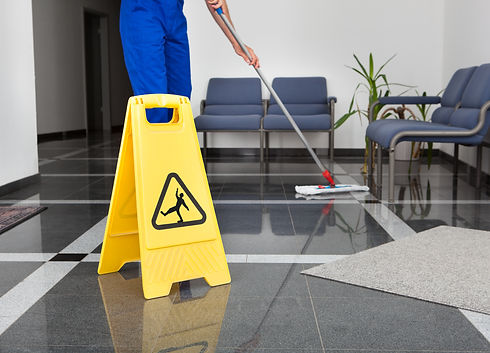 A man cleaning the floor with a mop and a wet floor sign