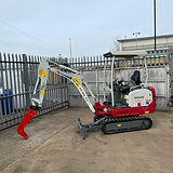 A small red and white excavator with a red attachment is parked on a concrete surface