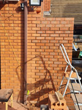 A brick wall with a ladder in front of it