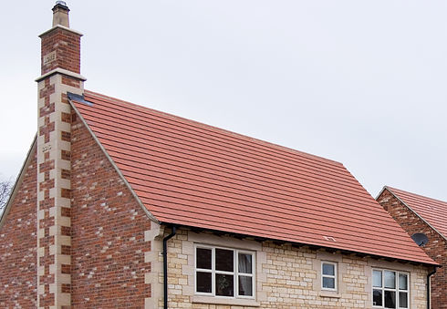 A modern house with a steep red-tiled roof and a brick chimney