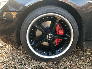 A black alloy wheel with red brake callipers