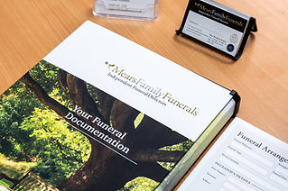 A file from 'Mears Family Funerals' titled 'Your Funeral Documentation' is open on a wooden table.