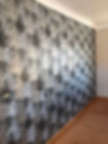 Wallpaper with black, white, and gold coloured tree branches printed on a grey background