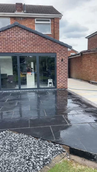 A wet patio area in front of a modern house with large glass doors