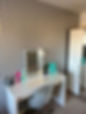 makeup table and mirror and a chair in front of a wallpapered wall