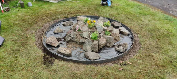 A circular garden area with a bed of rocks and flowers, freshly maintained