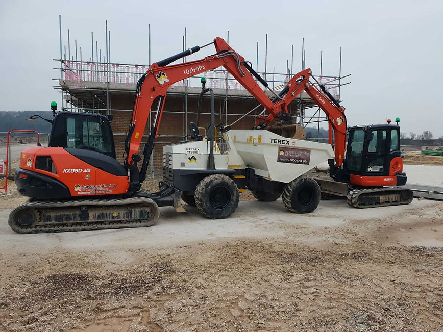 Kubota mini excavator and white dumper truck parked on a construction site