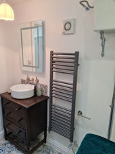 A round sink with a mahogany cabinet next to a drying rack