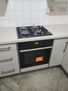 Black integrated gas hob and built-in electric oven set in light kitchen worktops