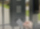 A hand holding a grey access card approaches a keypad entry system mounted on a gate