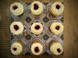 Nine elegantly decorated cupcakes with swirled frosting and berry filling