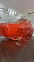 A freshly painted red vintage car partially covered with plastic sheets