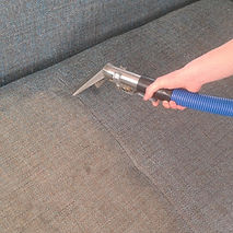 A professional cleaning a sofa using an equipment
