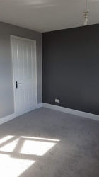 An empty room of a house with different shades of grey walls and a light grey carpet