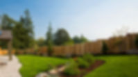 Sunny back garden of a house with wooden fencing and a patio