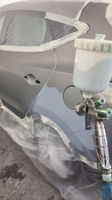 The car door being prepped for painting with a spray gun