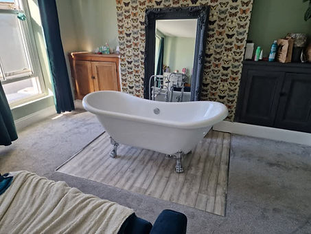 Freestanding white bathtub on a striped rug in a cosy room