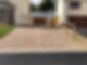 Paved driveway of a modern home leading to a garage, with a wooden fence on the side
