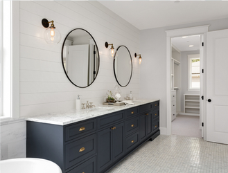 Luxury double vanity unit in dark blue with marble worktop, dual round mirrors, and bright wall sconces