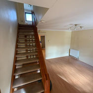 An empty spacious interior with wooden stairs and light-coloured walls