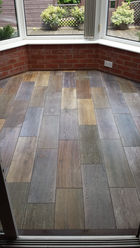 An area with wooden floor tiles and multiple windows