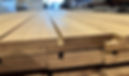 Close-up of neatly stacked, light brown wooden planks with smooth surfaces and precise edges