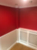 A bright red wall with white moulding and the lower part painted beige