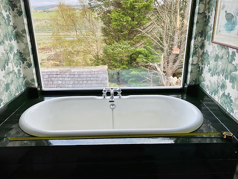 Oval bathtub with scenic window view in a wallpapered bathroom
