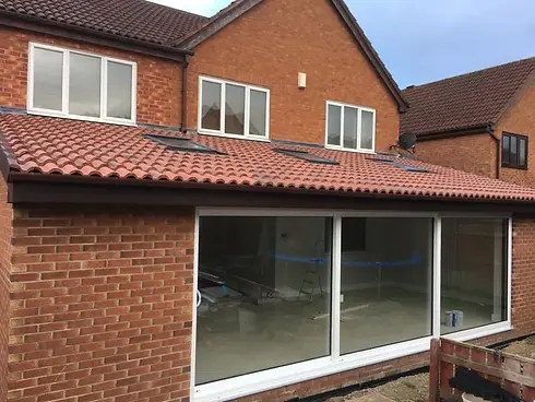 A red-tiled roof, brick house with a large glass sliding door
