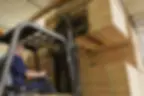 A professional stacking large bundles of frames in a warehouse