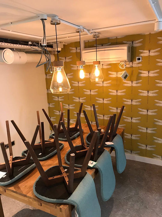 Office meeting room with hanging filament pendant lights and chairs stacked on table