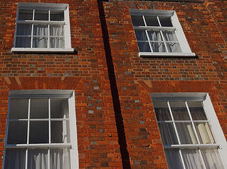 A brick building façade with two white-framed windows