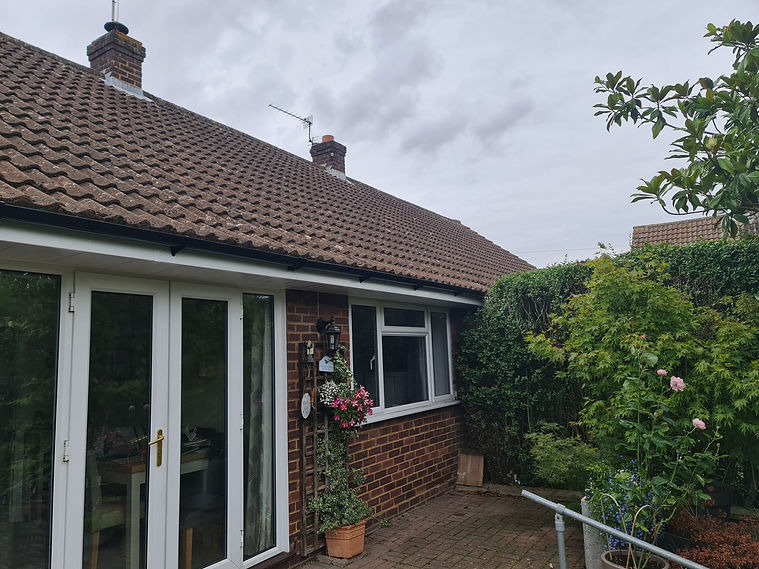 A tiled roof, white-framed glass doors, and a lush garden