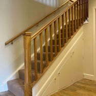 Polished wooden staircase with a matching handrail and built-in under-stairs storage cupboard