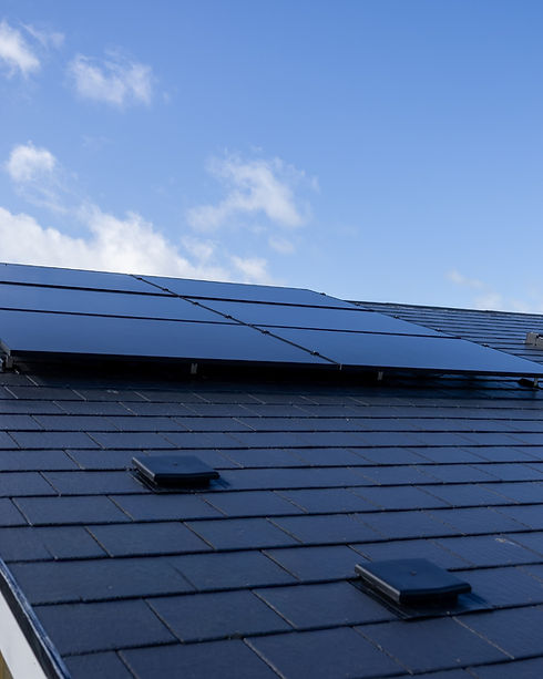 All black solar panel array installed on a dark slate tiled house roof