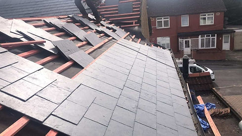 A worker installs slate tiles on a house roof