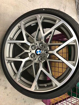 A silver alloy wheel with a BMW logo