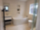 Modern bathroom featuring a bathtub, sleek vanity with a mirror, and a glass shower