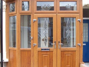 A wooden entrance with two glass-panelled doors and decorative glass accents