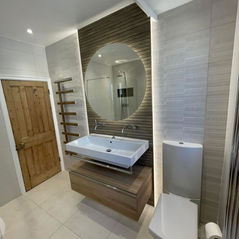 Modern vanity unit with round mirror in custom tiled bathroom