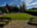 The front garden of a cottage with multiple chairs, tables, and benches