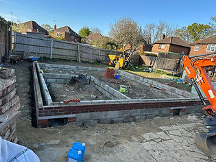 Construction site showing a partially built foundation made of bricks and concrete blocks