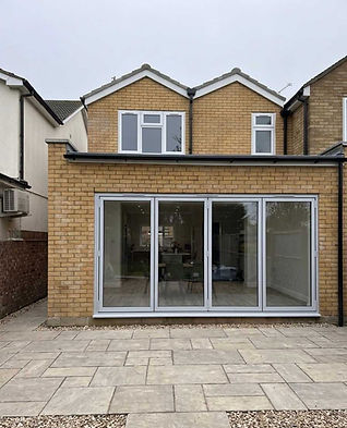 Exterior view of a modern house extension with large grey sliding glass doors