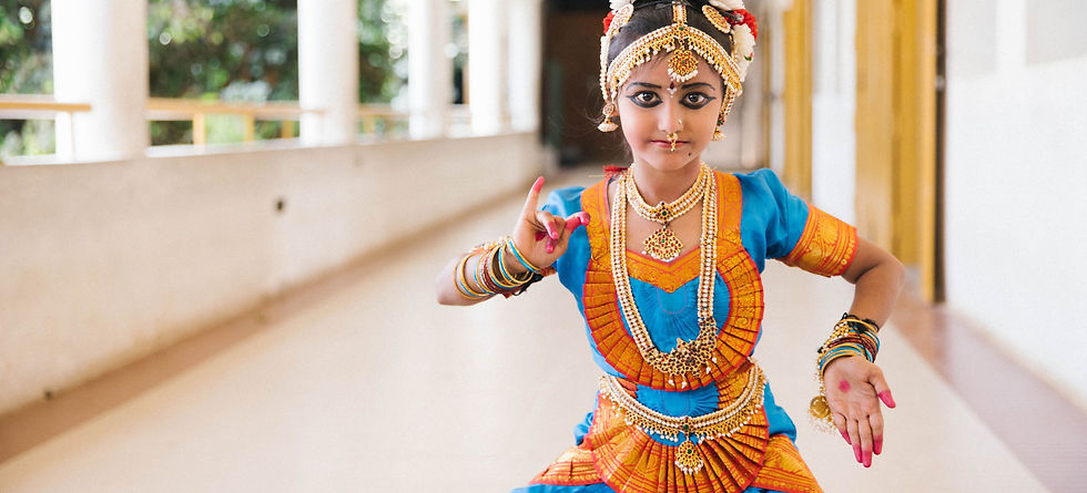 Young dancer in bright blue and orange traditional attire performs a classical Indian pose