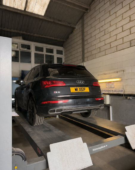 Black Audi Q5 SUV raised on a hydraulic lift inside a garage